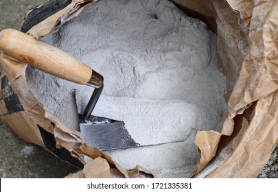 Close Up Trowel And Cement Powder In Paper Bag.