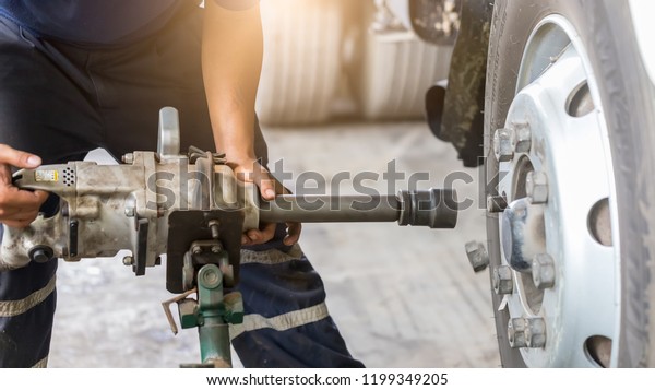 Close up of Truck Wheel mechanic hands using a\
pneumatic gun to loosen a wheel nut in a mechanical workshop  in\
the Truck Service Center.