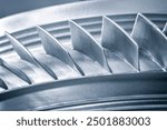 A close up of a turbine blade with a silver color. Concept of precision and engineering, as the blade is a crucial component of a turbine. The focus on the blade highlights its intricate design