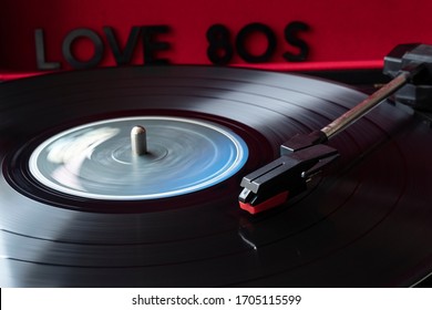 Close Up To A Turn Table Needle Playing A LP Vinyl Disc With Turn Table And I Love 80s Lettering Over Red Background. Music Lovers Concept