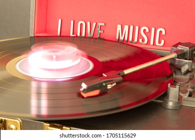 Close Up To A Turn Table Needle Playing A LP Vinyl Disc With Turn Table And I Love Music Lettering Over Red Background. Music Lovers Concept. Long Exposure Photography