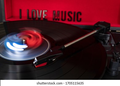 Close Up To A Turn Table Needle Playing A LP Vinyl Disc With Turn Table And I Love Music Lettering Over Red Background. Music Lovers Concept. Long Exposure Photography