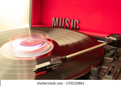 Close Up To A Turn Table Needle Playing A LP Vinyl Disc With Turn Table And MUSIC Lettering Word Over Red Background. Music Lovers Concept. Long Exposure Photography