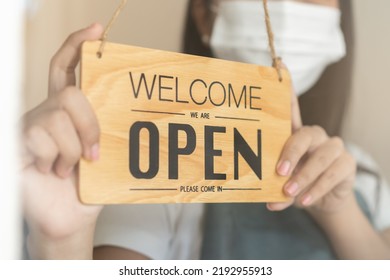 Close up turning sign board open, asian young owner retail, coffee shop woman wearing face mask, protect to pandemic of coronavirus, reopen store after close lockdown quarantine in covid-19. - Shutterstock ID 2192955913