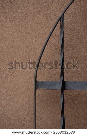 close up of twisted iron railing against beige painted concrete background vertical lines with twisted shape rod iron or metal gate posts vertical image format room for type vertical lines empty space