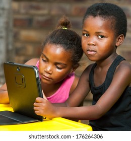 Close Up Of Two African Kids Doing Homework On Tablet Outdoors.