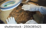 Close up of two archaeologists in gloves carefully opening ancient Egyptian papyrus on table in archaeological lab. Scientists work with cultural heritage of extinct human civilization. Archaeology.