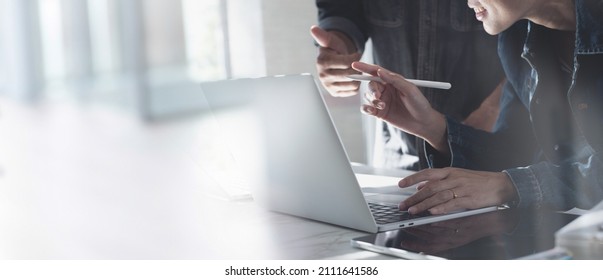 Close Up Of Two Asian Colleagues Working Together, Have A Discussion And Using Laptop Computer At Office With Financial Document On Desk In Modern Office, Startup Business, Teamwork Concept