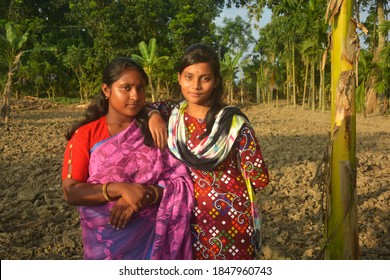 Close up of two beautiful Indian Bengali Teenage girls wearing pink sari and salwar kameez with  earrings nose pin posing in a plowed agricultural field one hand on shoulder, selective focusing - Shutterstock ID 1847960743