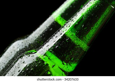 Close up of two beer bottles over black background