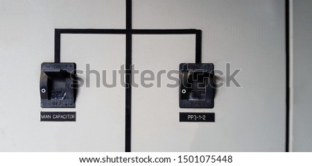Close up Two black  electrical main breaker connect each other on gray or grey stainless steel cabinet for distribution electric current to switch or device with copy space in the power room 