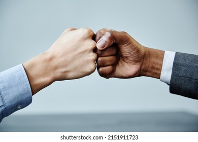 Close up of two business partners fistbumping in unity at meeting table, copy space