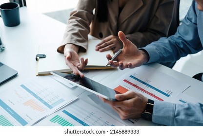 Close up two business partnership coworkers discussing a financial planning on digital tablet and paperwork. - Powered by Shutterstock