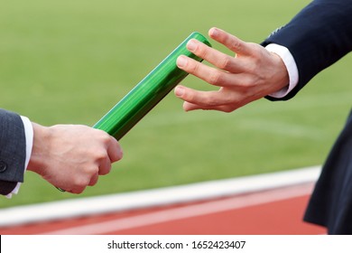 Close up of two businessman hands passing baton in relay race
