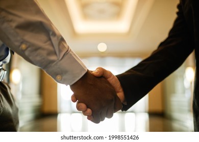 Close Up Of Two Businessmen Shaking Hands In Office Building Hall, Copy Space