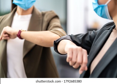 Nahaufnahme von zwei Geschäftsfrauen machen alternativen Grußgeschmack im neuen normalen Büroleben. Sie tragen eine Schutzmaske und verwenden Ellenbogenbumpe anstelle von Handschütteln, um die Infektion mit Coronavirus COVID-19 zu verringern.