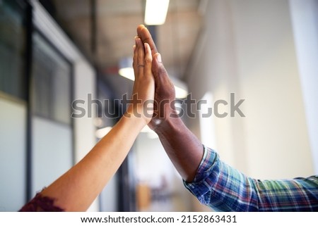 A close up of two diverse hands giving a hi-five celebration in the office
