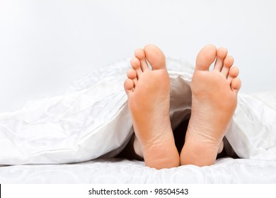 Close Up Of Two Feet In A Bed