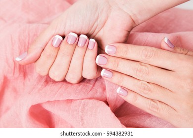 Close Up Of Two Female Caucasian Hands With Beautiful Pink French Manicure Isolated On Fabric. Horizontal Color Photography