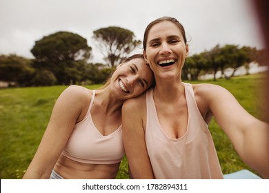 Close up of two female friends in park for a workout. Women in fitness wear relaxing and having fun after workout. - Powered by Shutterstock