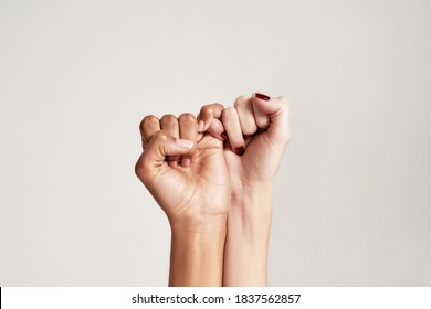 Close up of two female hands making a pinkie promise sign isolated over grey background. The symbol of commitment. Selective focus. Horizontal shot