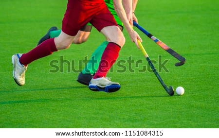 Close up of two field hockey players, challenging eachother for the control and posession of the ball during an intense, competitive match on professional level