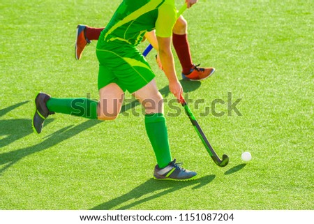 Close up of two field hockey players, challenging eachother for the control and posession of the ball during an intense, competitive match on professional level