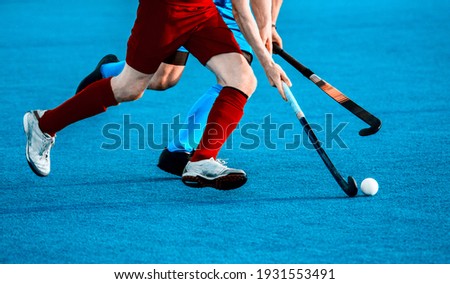 Close up of two field hockey players, challenging eachother for the control and posession of the ball during an intense, competitive match on professional level. Vintage color filter