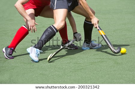 Close up of two field hockey players, challenging eachother for the control and posession of the ball during an intense, competitive match on professional level