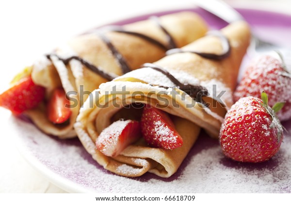 close up of two french style crepes, shallow\
dof. Some ingredients in the\
background
