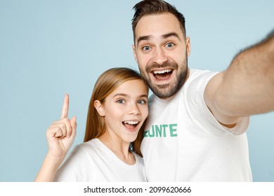 Close Up Two Fun Young Friends Couple Teen Girl Man Wears White T-shirt Green Title Volunteer Doing Selfie Isolated On Pastel Blue Color Background. Voluntary Free Team Work Help Charity Grace Concept