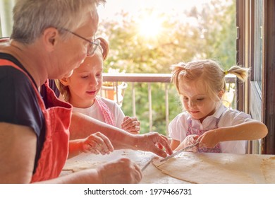 Close Up Of Two Girls Cooking Pasta With Grandma. Funny Moment Of Two Children Learning How To Make Pasta With Grandma.