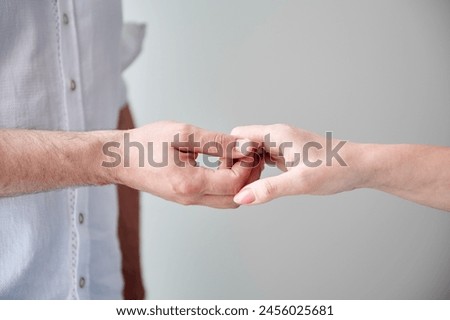 Close up of two hands engaging in delicate touch. Man's and woman's hands on white neutral background. Husband holding hand of his lovely wife. Concept of love, intimacy, support, and trust.