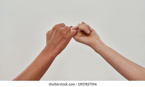 Close up of two hands hook little finger together to promise or asking for asking for reconciliation isolated over light background. Web Banner - Shutterstock ID 1907837596