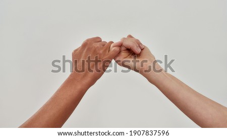 Close up of two hands hook little finger together to promise or asking for asking for reconciliation isolated over light background. Web Banner