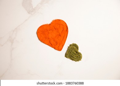 Close Up To Two Heart Shapes Of Spices On Light Marble Background. Heart Silhouettes Of Dried Basil And Paprika Powder. Spicy Love Symbols. Little Hearts On Marble Kitchen Table. Still Life