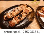 close up of two Japanese grilled roasted chicken skewer yakitori on a black plate with copy space