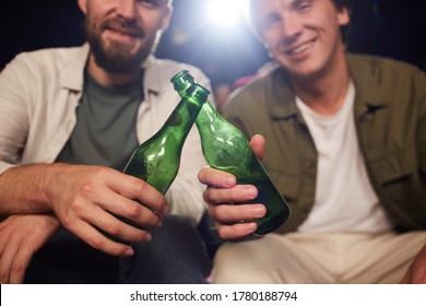Close up of two male friends smiling and clinking beer bottles while watching movie in cinema theater, copy space - Shutterstock ID 1780188794