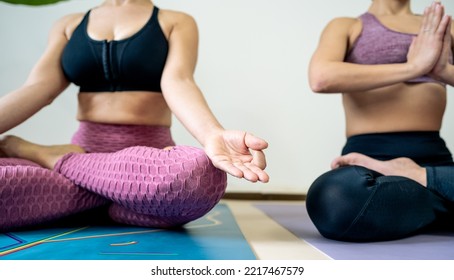 Close Up Of Two Mature Women Practing Yoga Meditation Exercise At Home