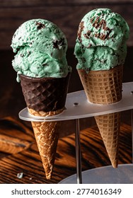 A close up of two mint chocolate chip ice cream cones in a stand.