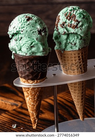 A close up of two mint chocolate chip ice cream cones in a stand.