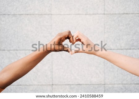 Close up of two multicultural hands join together form heart with background wall. Hope and love between homosexual relationships, human beings of different races with different skin color. Copy space