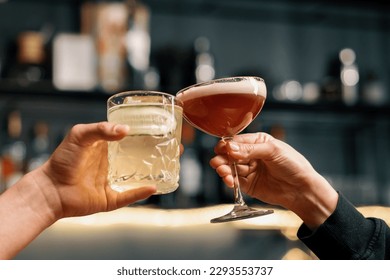Close up of two people cheering cocktails in bar or disco club drinks and cocktails concept