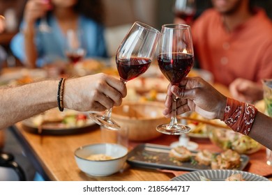 Close up of two people clinking wine glasses during dinner party in cozy setting, copy space - Powered by Shutterstock