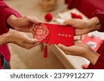 Close up of two people handing ornate red envelope as Chinese New Year tradition for good luck Have overflowing abundance every year