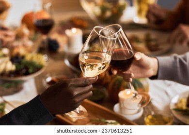 Close up of two people holding wine glasses and toasting in celebration at dinner table, copy space - Powered by Shutterstock