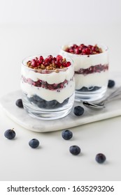 A Close Up Of Two Pomegranate And Blueberry Parfaits Layered With Vanilla Greek Yogurt And Granola.