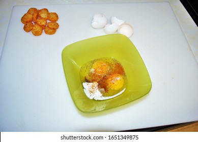 Close Up Of Two Raw Seasoned Eggs In A Green Plastic Bowl Hash Browns And Eggshells