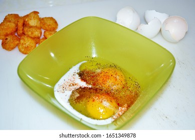 Close Up Of Two Raw Seasoned Eggs In A Green Plastic Bowl Hash Browns And Eggshells