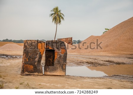 Close up of two rusted and brown colored broken oil drums at the beach